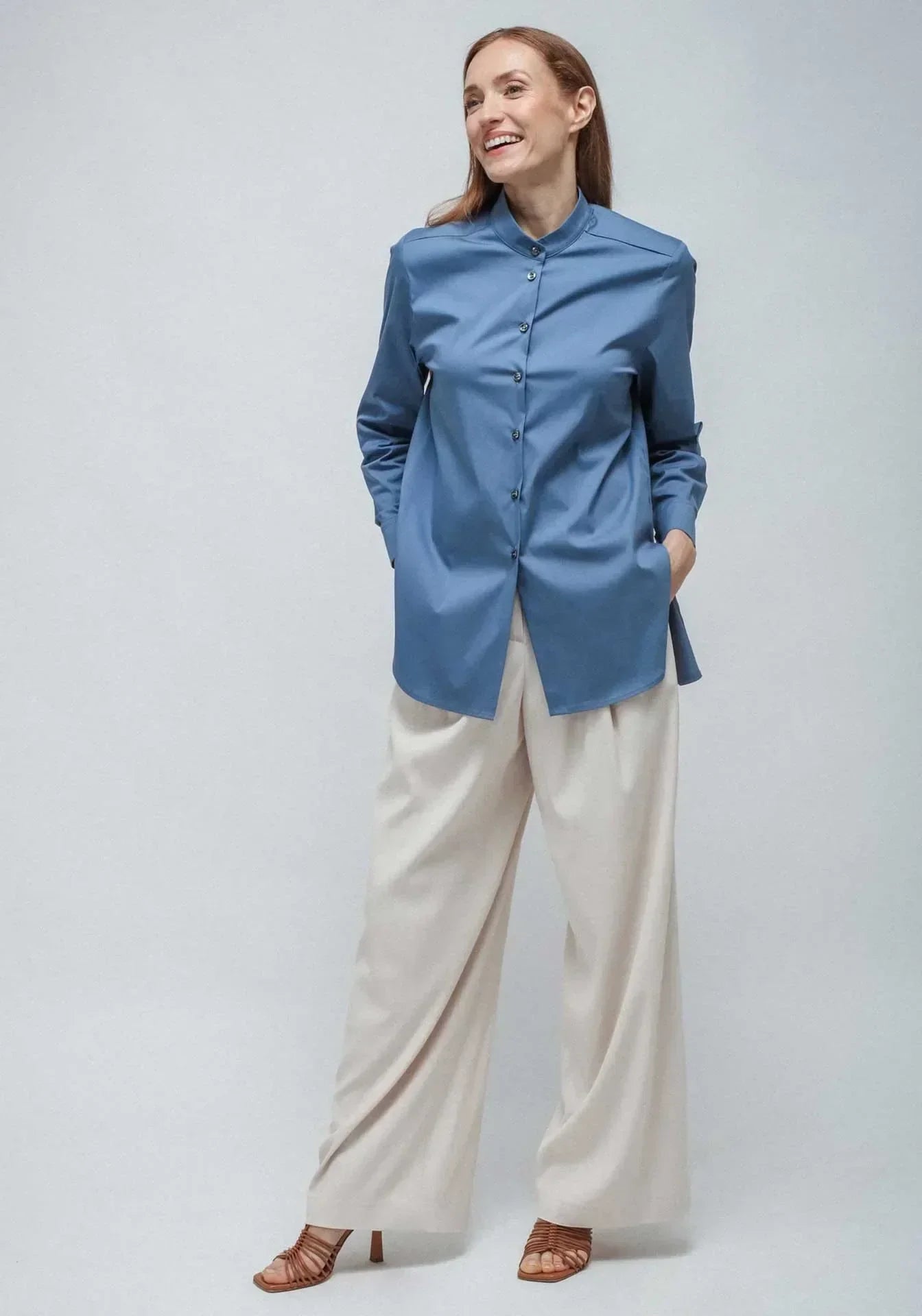 A woman wearing a korean long shirt in blue, and white palazzo pants from Humans & Land (H&L) standing on a white seamless background