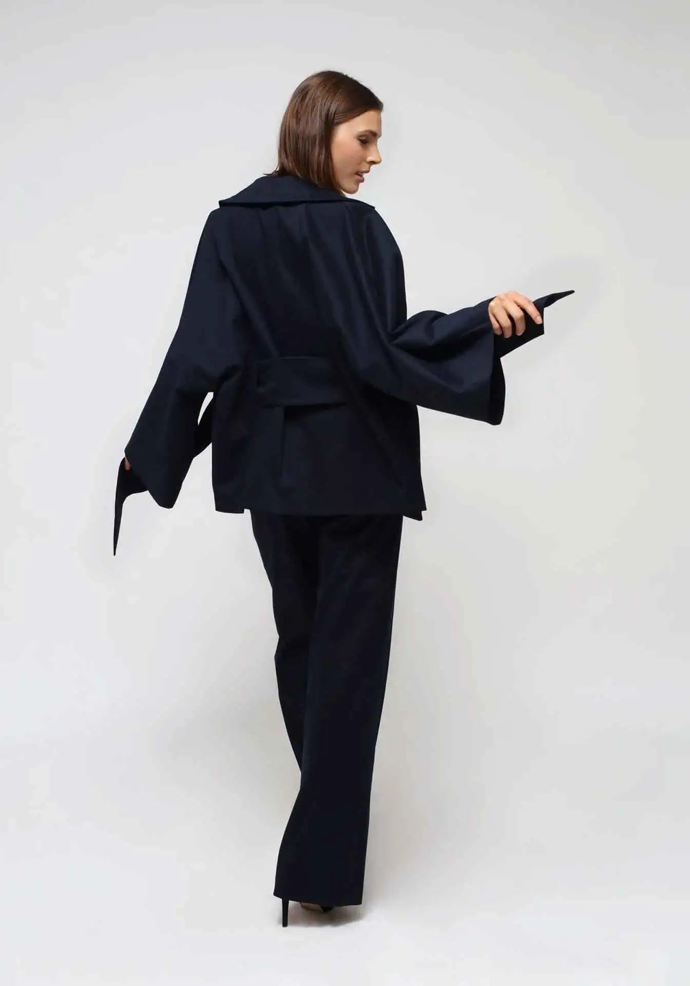 A woman in white background is wearing a blue kimono jacket and pants.