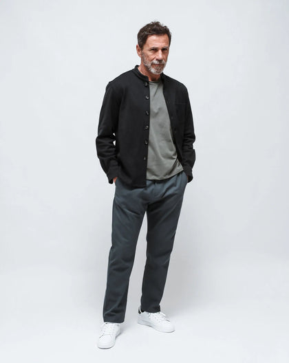 A men wearing a Navy Blue Punto Milano shirt-jacket with Korean collar, a military green cotton t-shirt, and light blue long pant standing in a white seamless background.