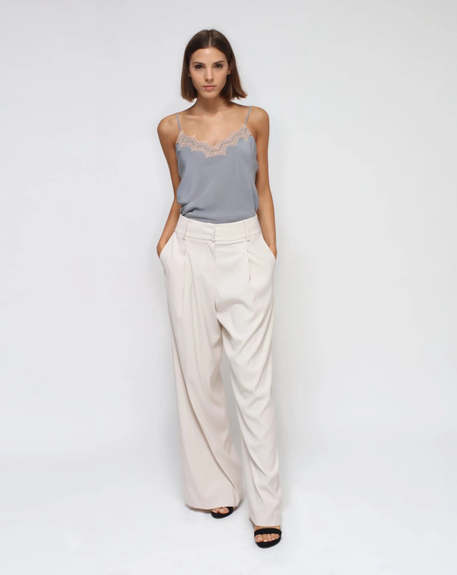 A model wearing a gray silk laced lingerie top with a white palazzo pants.