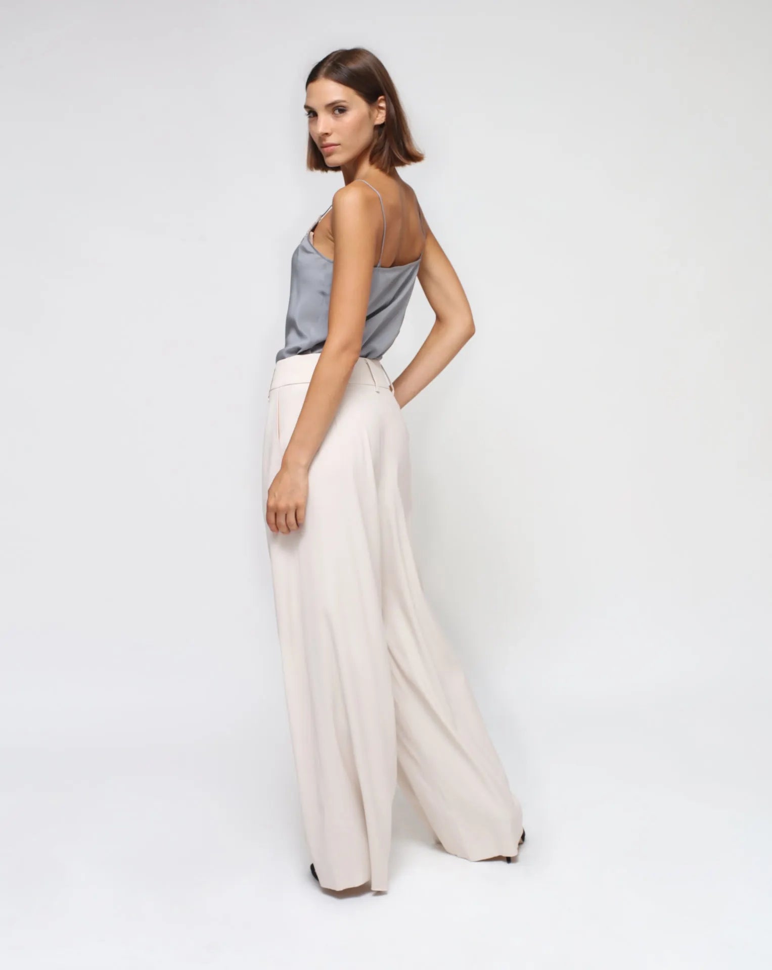 A model wearing a gray silk laced lingerie top with a white palazzo pants.