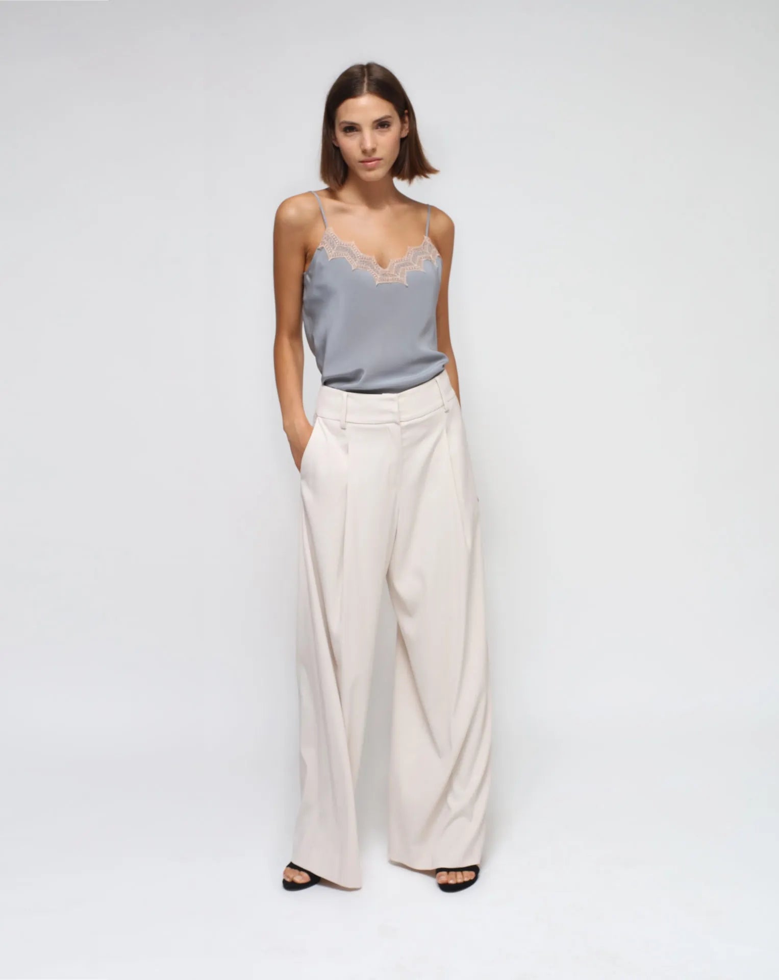 A model wearing a gray silk laced lingerie top with a white palazzo pants.