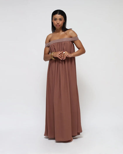 A woman standing on a white background with a brown silk dress.