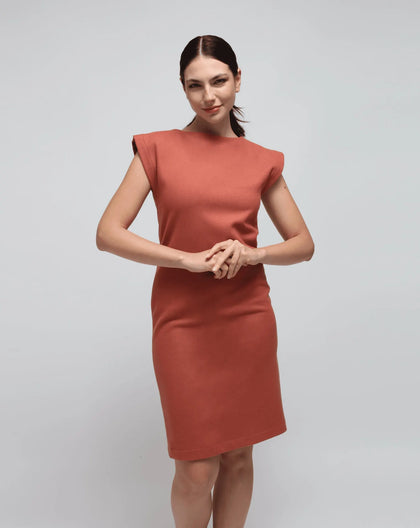 A woman modeling a pink sheath dress with a round neckline and 3/4 sleeves, featuring a straight-leg cut.