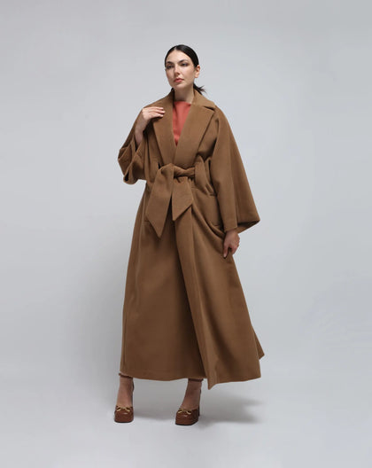 A woman wearing a kimono inspired wool coat in color camel.