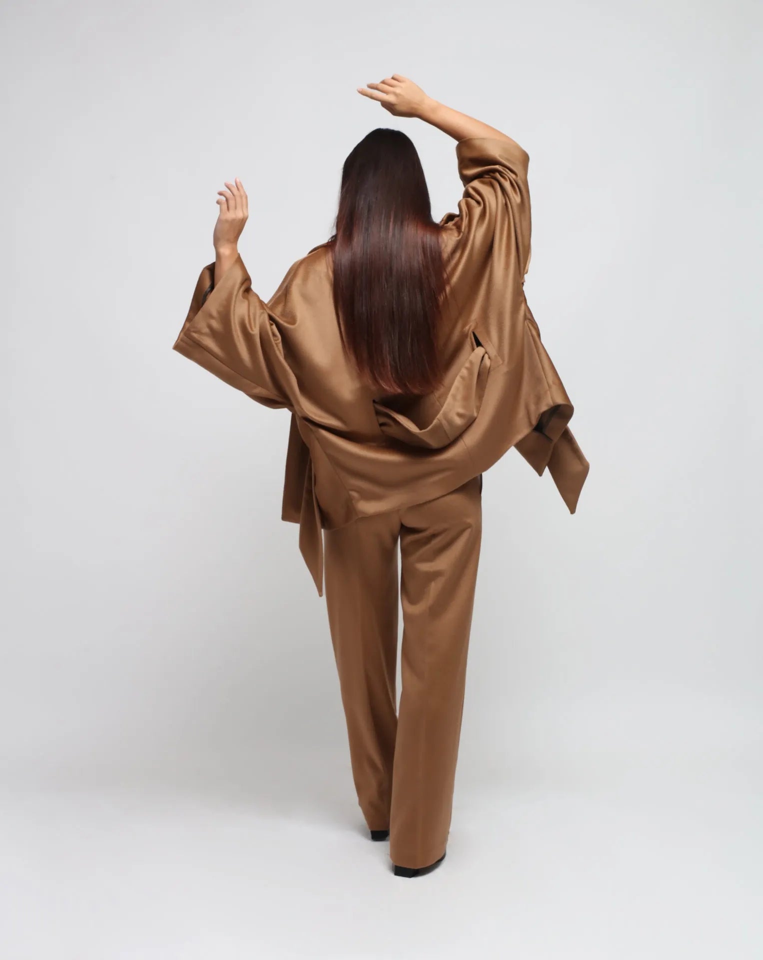 Woman wearing a camel kimono and straight pants on white seamless background.