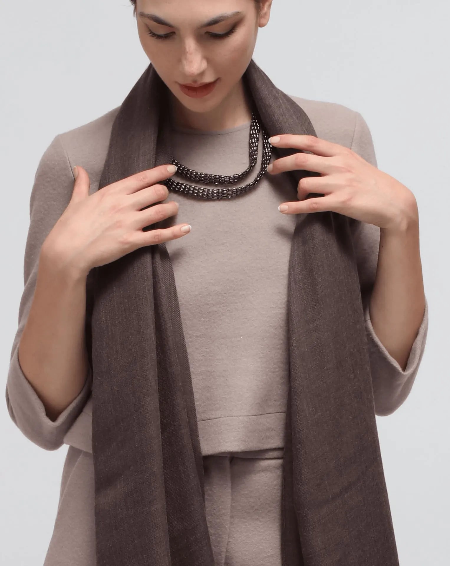 A woman wearing an oversized brown cashmere scarf draped over her shoulders.