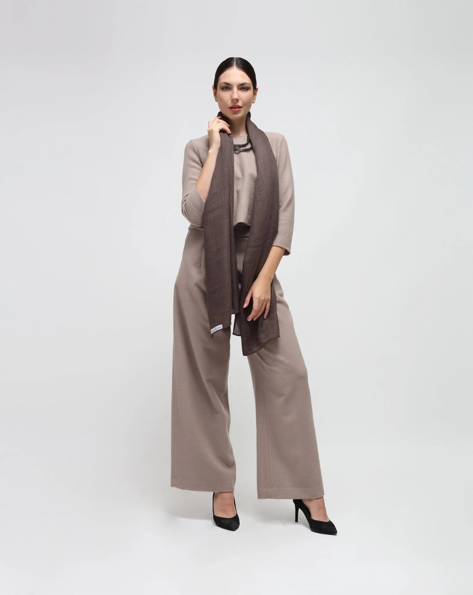 A woman wearing an oversized brown cashmere scarf draped over her shoulders.