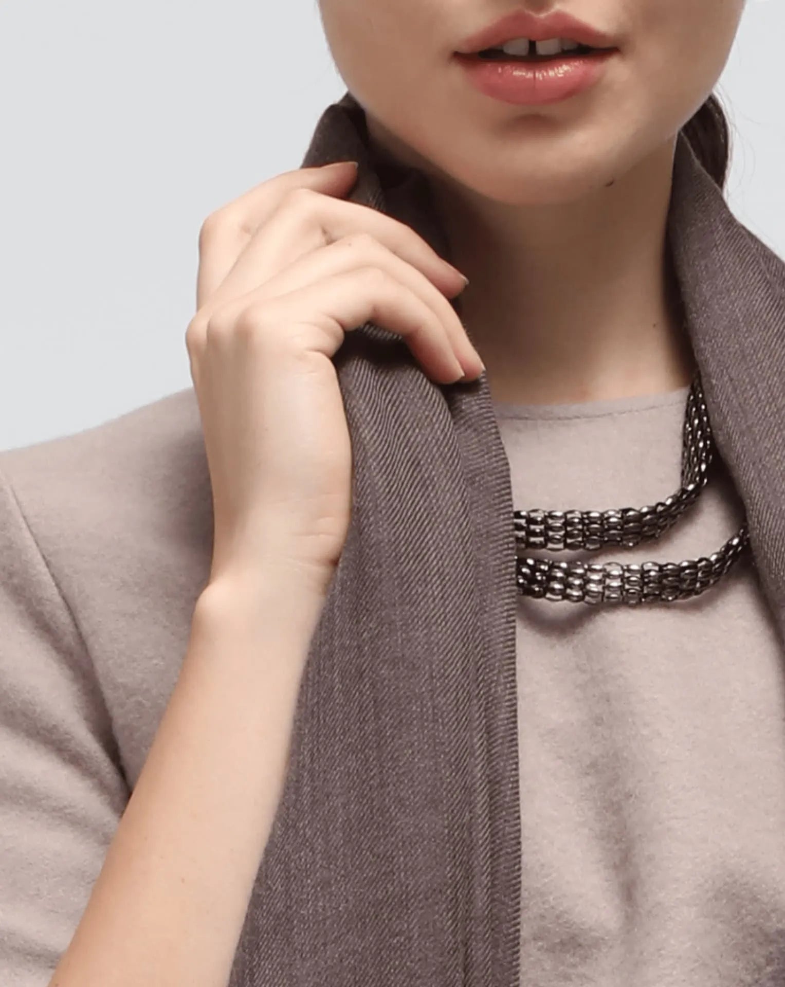 A detail of a woman wearing an oversized brown cashmere scarf draped over her shoulders.