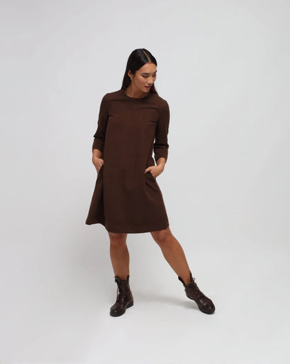 Woman in white background with brown flared dress in brown.