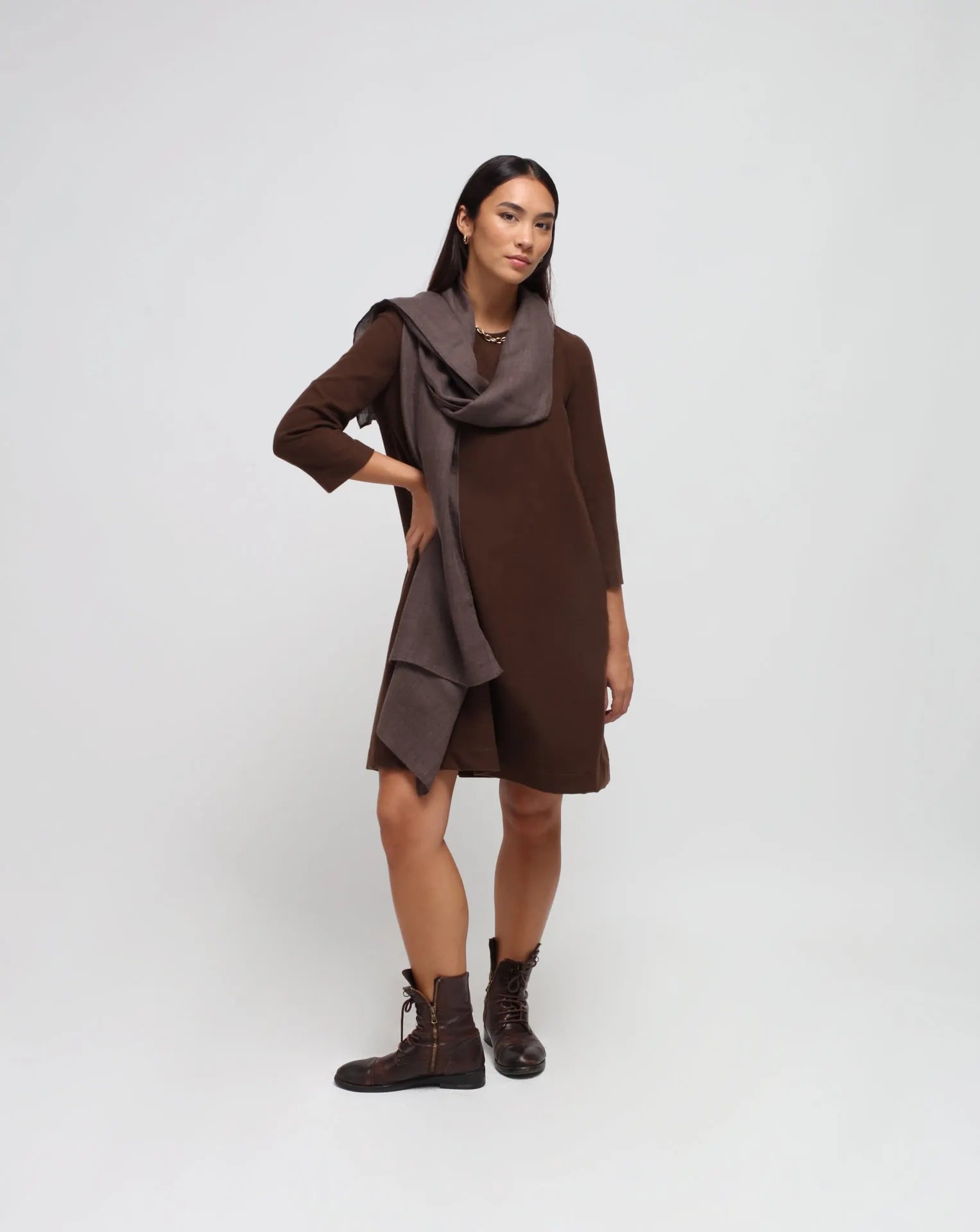 Woman in white background with brown flared dress in brown.