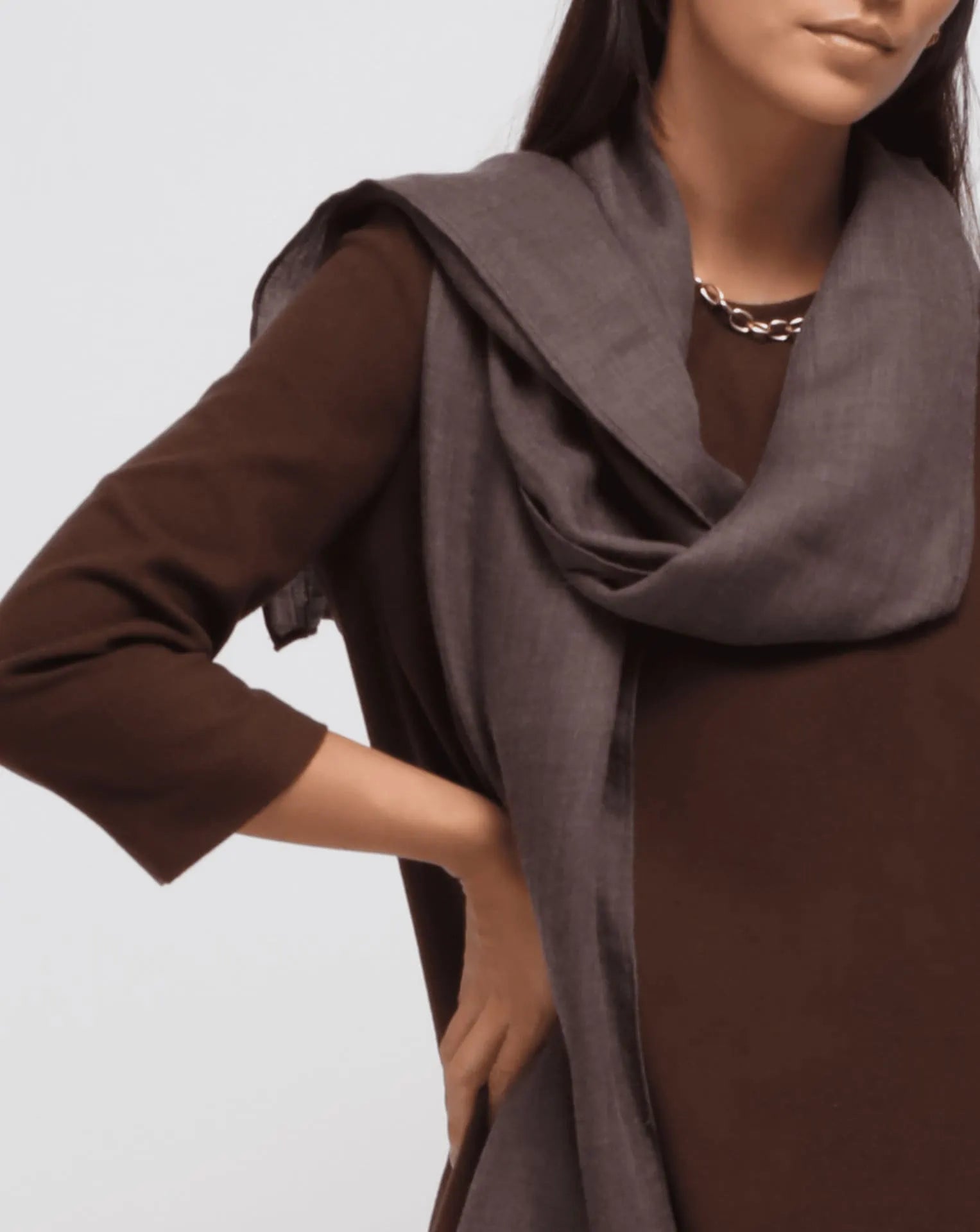 A detail of a woman wearing an oversized brown cashmere scarf draped over her shoulders.