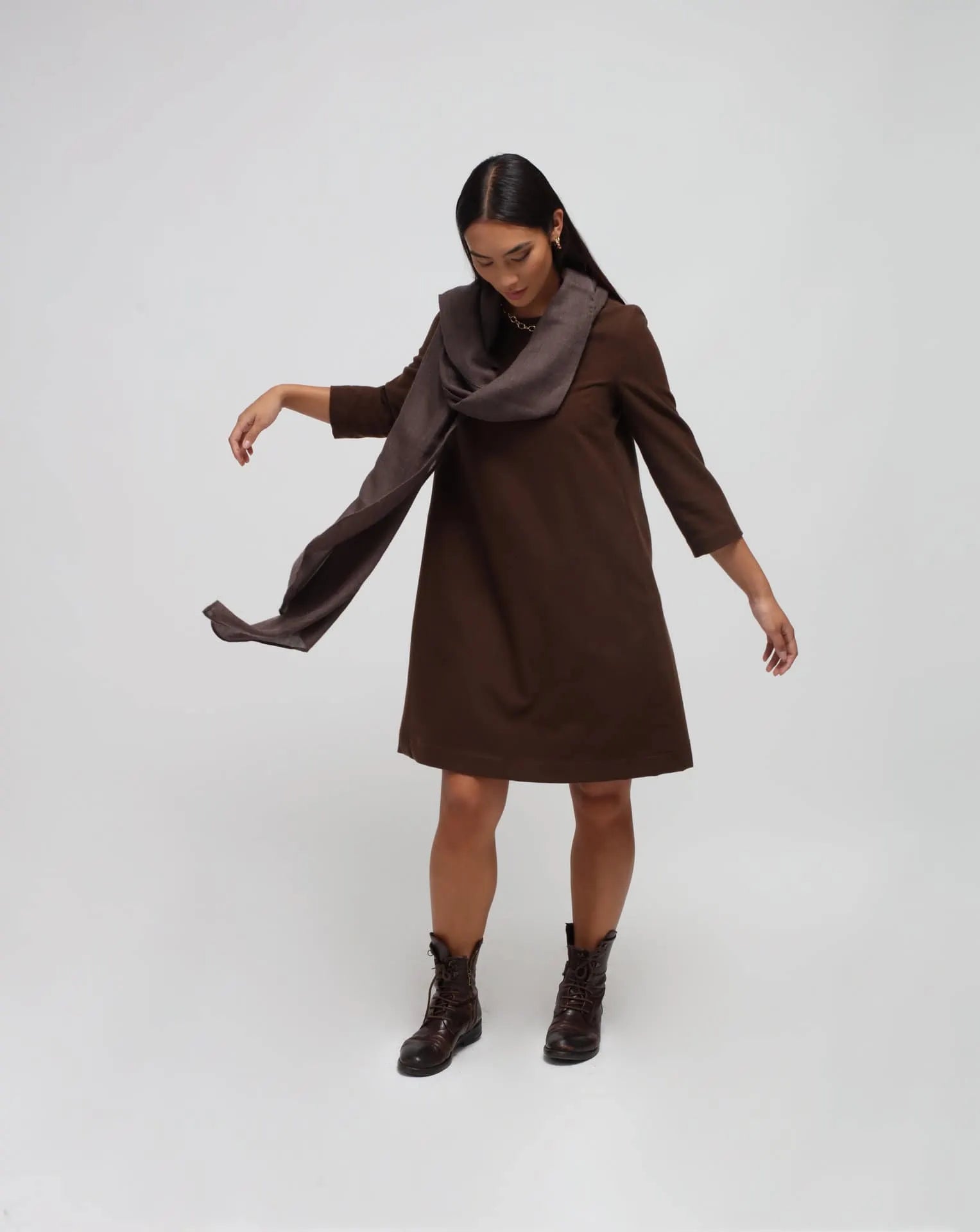 Woman in white background with brown flared dress in brown.
