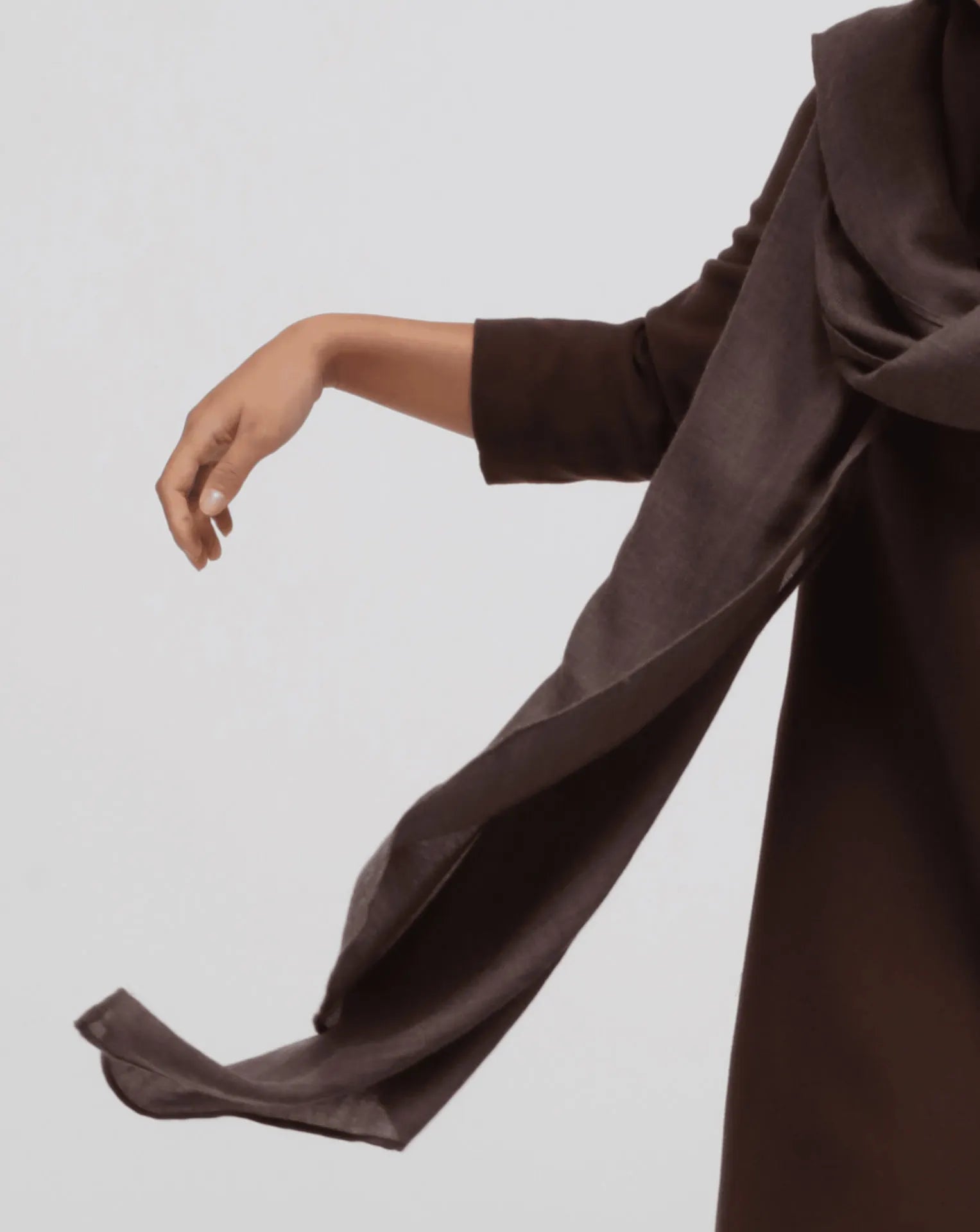 A detail of a woman wearing an oversized brown cashmere scarf draped over her shoulders.