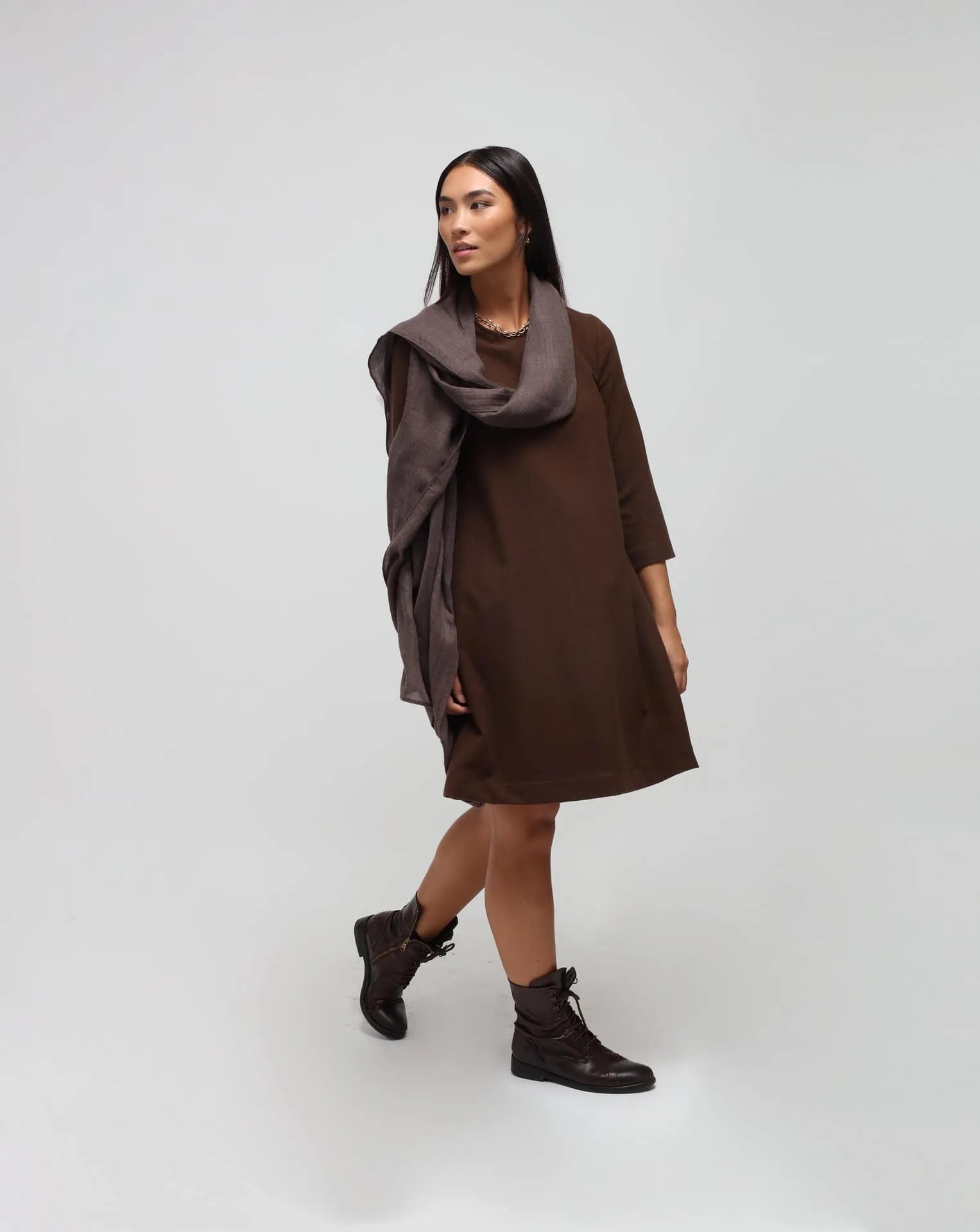 A woman wearing an oversized brown cashmere scarf draped over her shoulders.