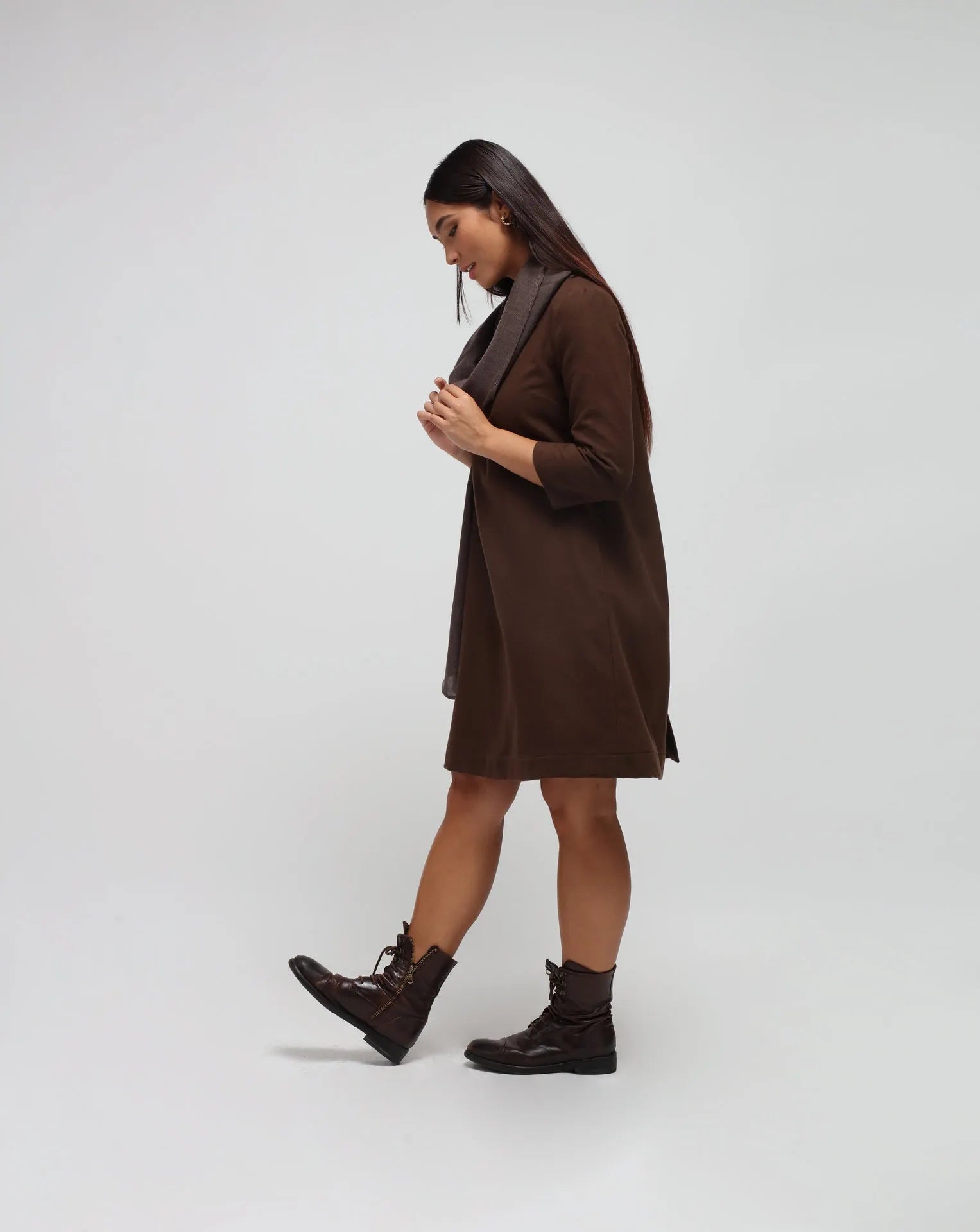 Woman in white background with brown flared dress in brown.