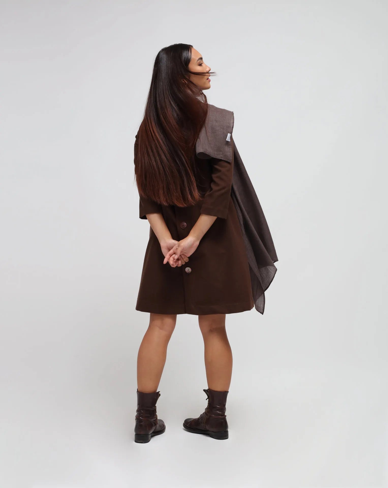 Woman in white background with brown flared dress in brown.