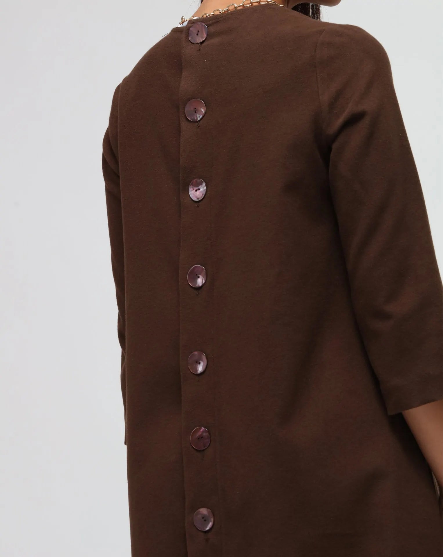 Woman in white background with brown flared dress in brown.