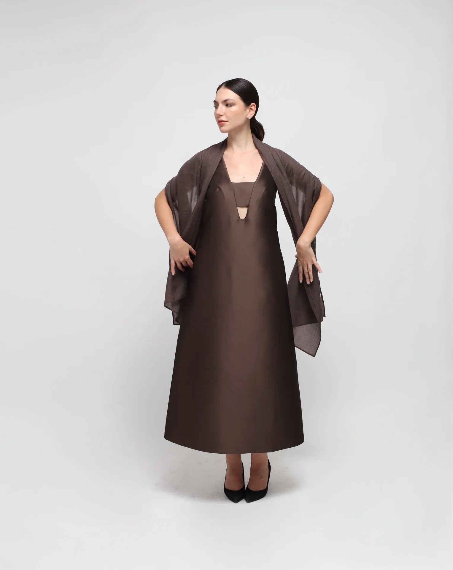 A woman wearing an oversized brown cashmere scarf draped over her shoulders.