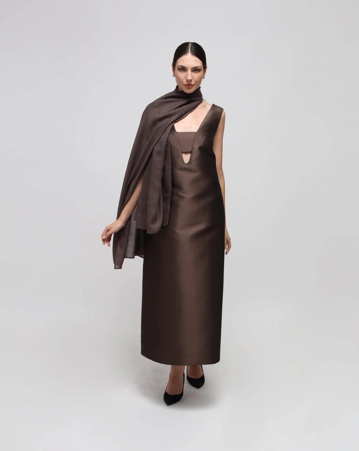 A woman wearing an oversized brown cashmere scarf draped over her shoulders.