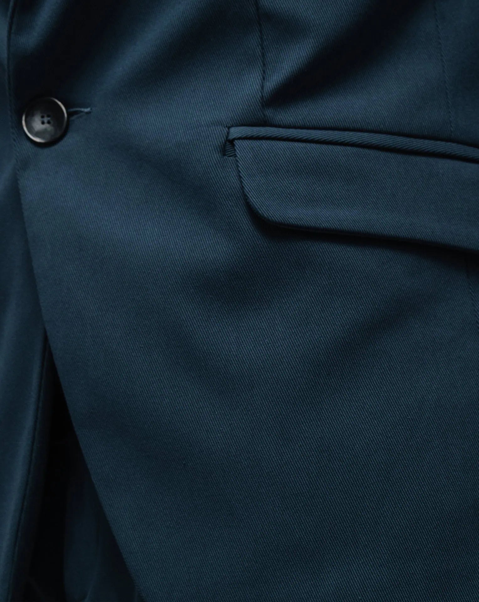A detail of the outside side pocket of a gabardine blue one-button jacket.