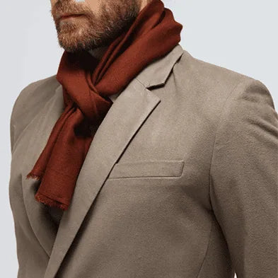 Man wearing a brown suit and rust-colored cashmere scarf on a white background