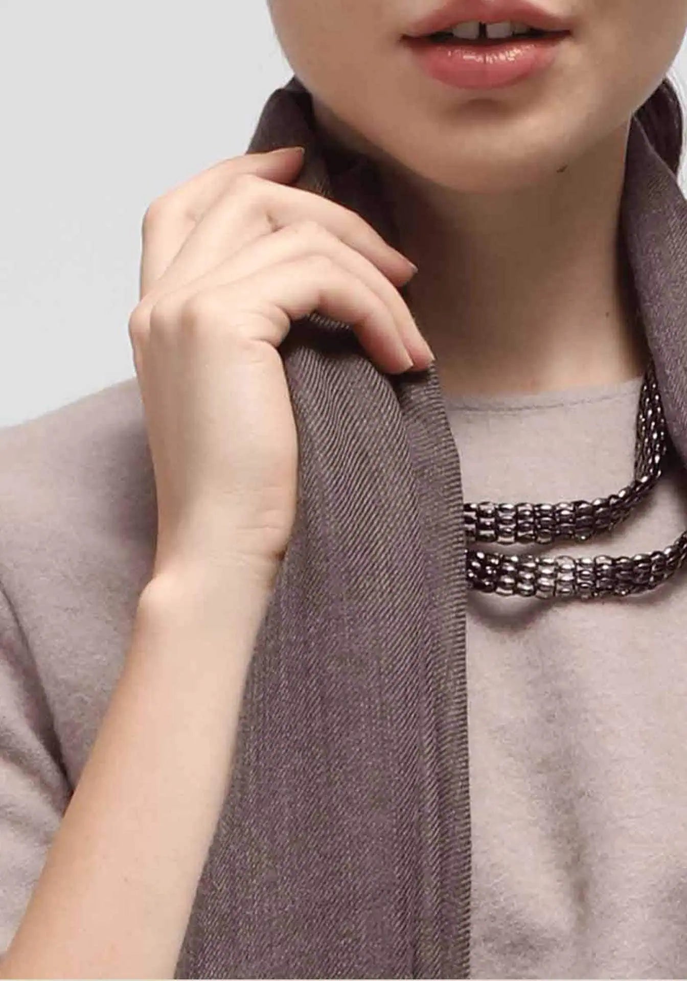 A close up of a woman wearing a brown scarf and silver necklace