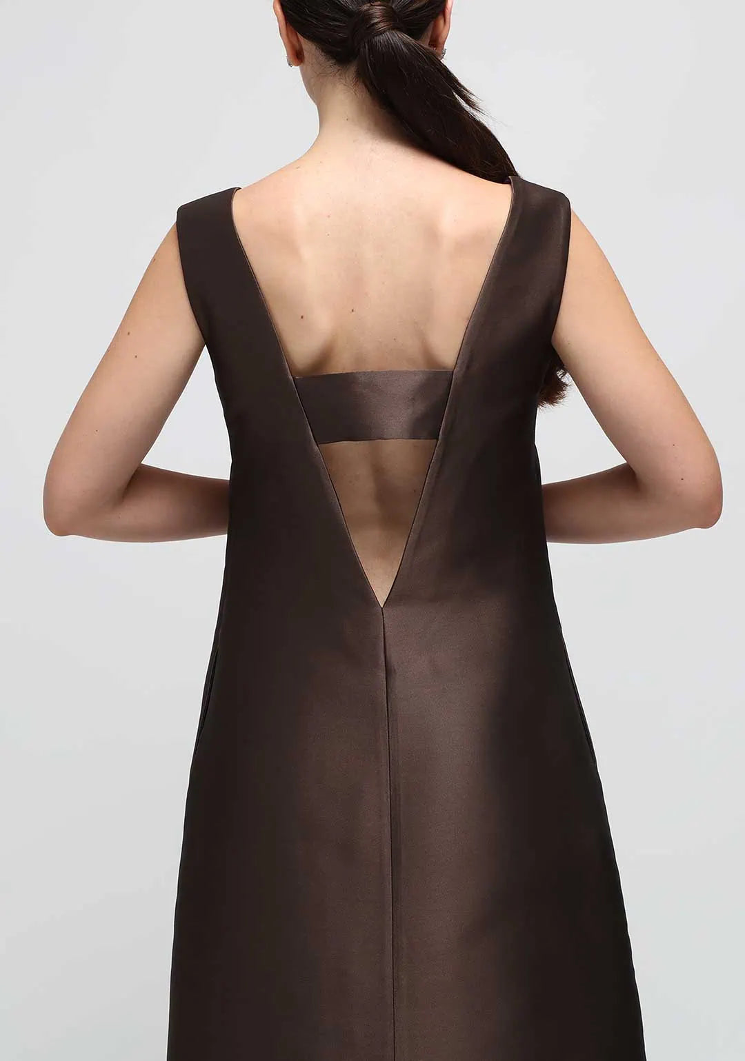 A woman wearing a brown satin dress open in the back with a V 