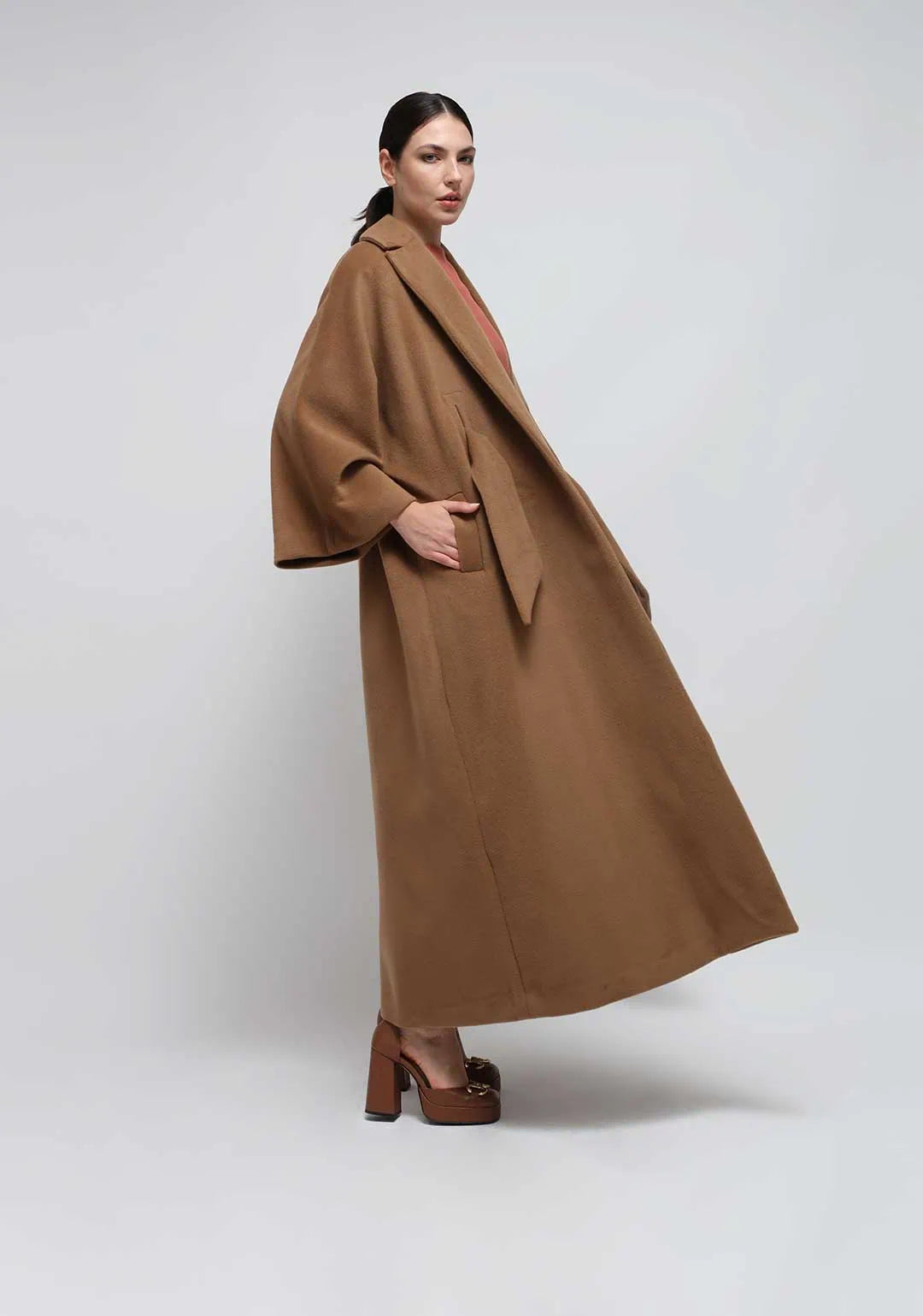 Luxury Fashion vs Fast Fashion That Lasts. A Camel Kimono coat worn by a woman in a white seamless background.