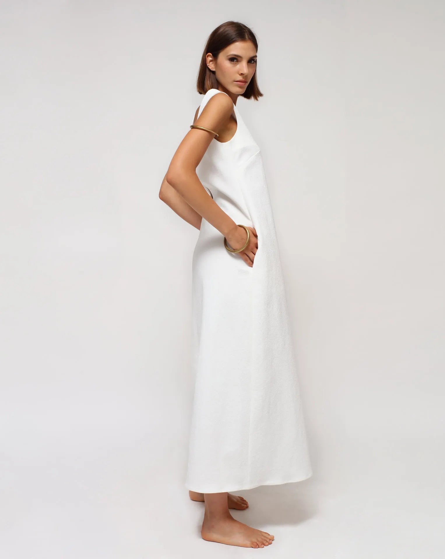 A woman wearing a white summer sleeveless dress on a white seamless background. 