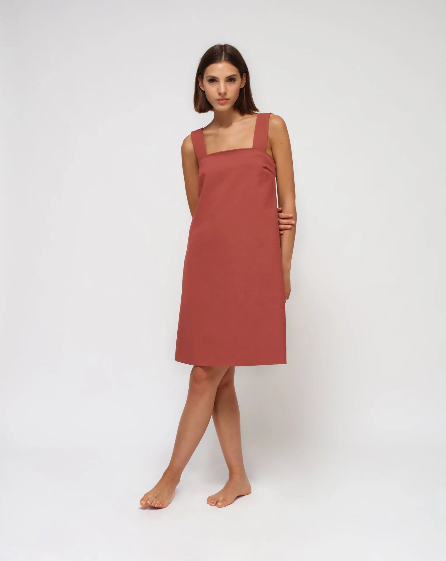 A woman wearing a summer cotton flared dress with straps on a white seamless background.