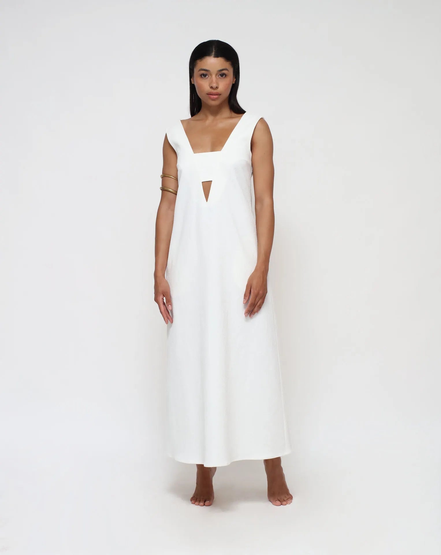 A woman wearing a V- front and back summer white dress on a white seamless background.