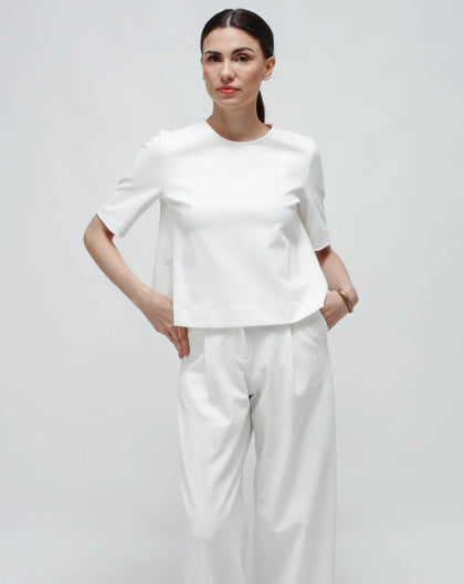 Person wearing a white outfit against a white background