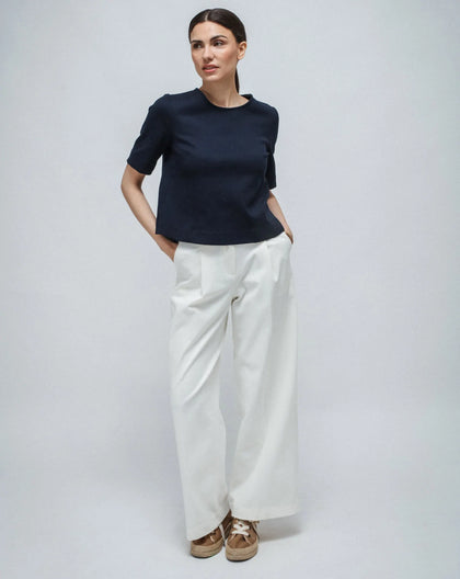 Woman with blue Punto Milano top short sleeves and white pants. 
