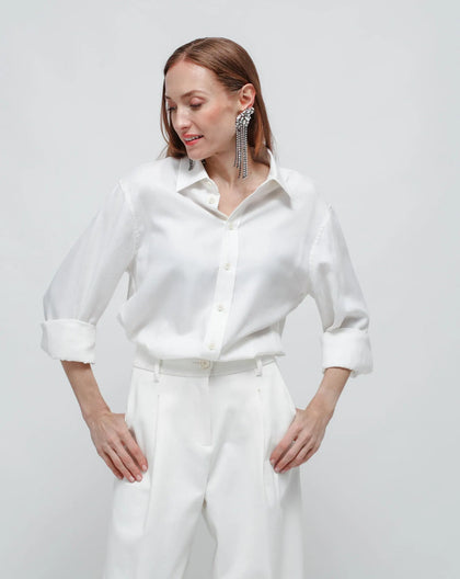 A person wearing a white shirt and pants, standing against a white background.