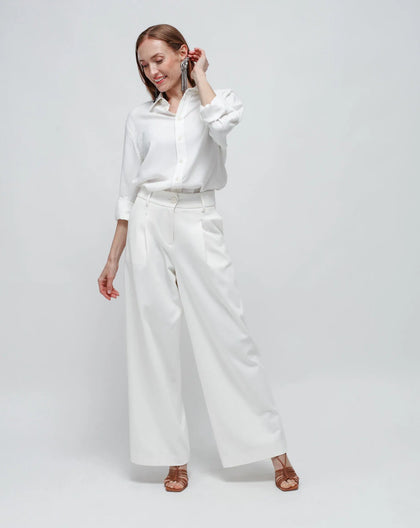 A women standing with white palazzo pants in punto Milano and a white shirt.