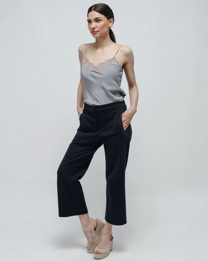 A model wearing 'Blue Traveller Pants in Punto Milano' with a plain grey top, standing against a white background.