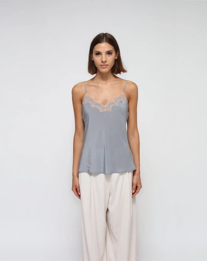 A model wearing a gray silk laced lingerie top with white palazzo pants.