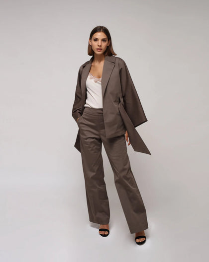 Woman in white background wearing a taupe color kimono jacket and pants with a cream lingerie top under.