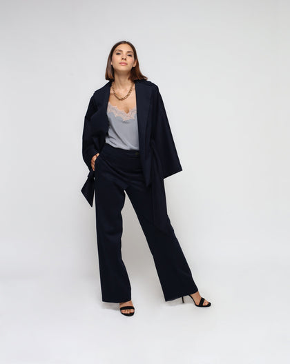 A woman standing against a white background, wearing a blue kimono jacket with matching pants, paired with a grey top and black shoes.