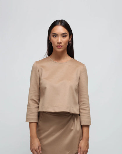 A woman with a camel flared top and back buttons.