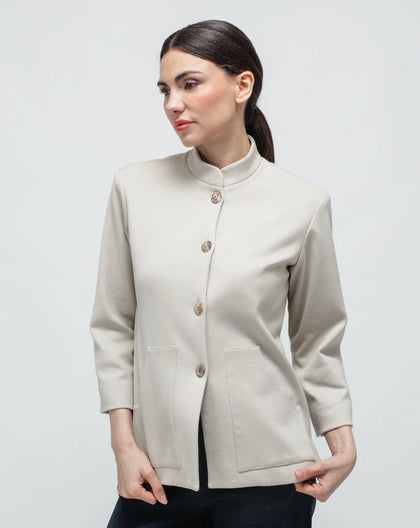 A woman wearing a beige Korean collar cardigan jacket with two front pockets and a small slit on the side. The jacket is buttoned in the front.