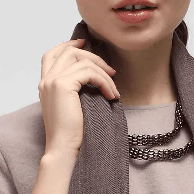 Woman wearing a brown scarf and necklace against a neutral background